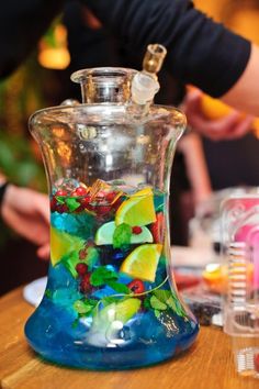 a glass vase filled with colorful gummy bears on top of a wooden table next to other items