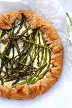 a pizza with asparagus and cream cheese on it sitting on top of wax paper