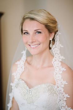 a woman wearing a wedding veil and smiling at the camera with her hair pulled back