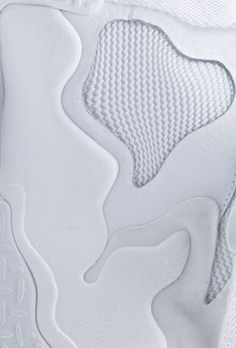 close up view of the upper part of a white tennis shoe with mesh on it