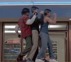 three young men standing in front of a store window with their arms up and fists raised