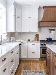 a kitchen with white cabinets and wood floors