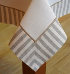 a close up of a table cloth on top of a wooden post with a white and gray stripe design