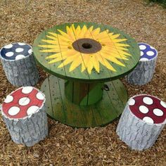 an outdoor table made out of logs and painted with sunflowers