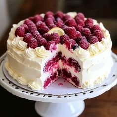 a cake with white frosting and raspberries on top sitting on a plate