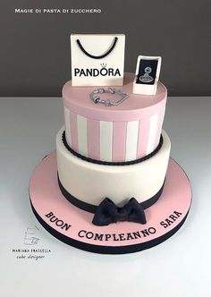 a pink and white cake with a bag on top that says pandara compleanoo sara