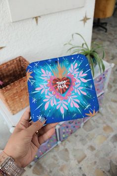 a person holding up a blue box with a heart on it and fireworks in the background