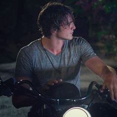 a young man riding on the back of a motorcycle in the dark with his hand on the handlebars