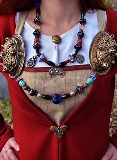 a woman wearing a red dress and some necklaces