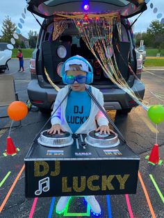 a young child in front of a dj's turntable with balloons and streamers