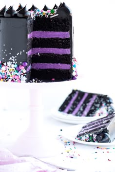 a slice of black cake with purple frosting and sprinkles