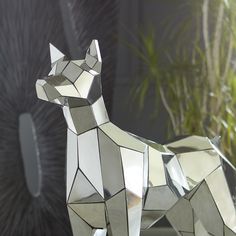 a metal dog statue sitting on top of a table next to a potted plant