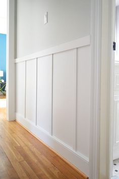 an empty room with white paneling and wood floors