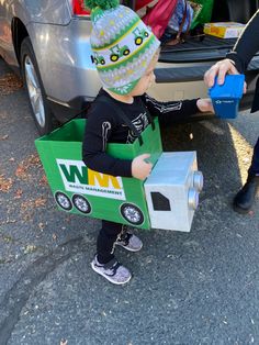 a small child in a box costume standing next to a car