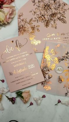 the wedding stationery is laid out on top of the table with pink flowers and gold foil