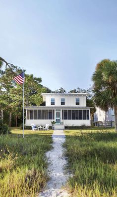 a white house sitting on top of a lush green field next to a flag pole