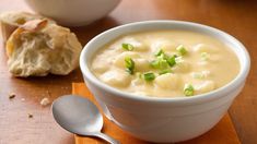 two bowls of soup with bread on the side