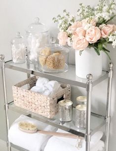 a shelf with towels, soaps and other items on it next to a vase filled with flowers