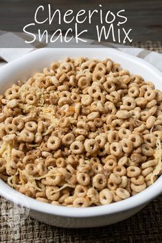 cheerios snack mix in a white bowl on top of a table with silverware