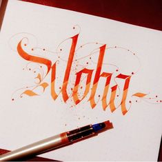 an orange ink pen sitting on top of a piece of paper with the word slobja written in cursive writing