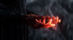 a person holding something in their hand with fire coming out of the backgroung