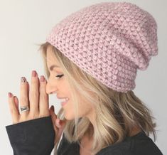 a woman wearing a pink crocheted hat and holding her hand up to her face