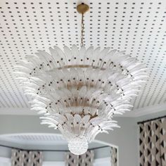 a chandelier hanging from the ceiling in a room with patterned walls and curtains