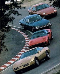 three different colored cars driving on a race track