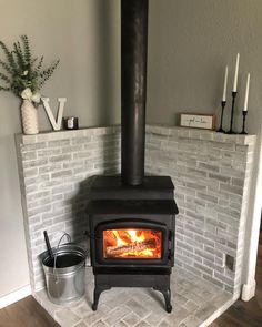 a wood burning stove sitting inside of a living room next to a brick wall and potted plant