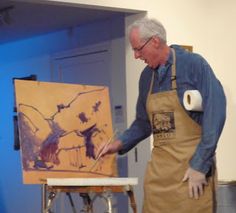 an older man is painting on the easel