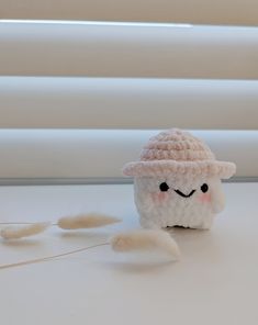 a small white stuffed animal with a hat on it's head next to feathers