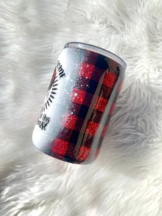 a red and black plaid pattern on a white furry surface with a can of beer in the foreground