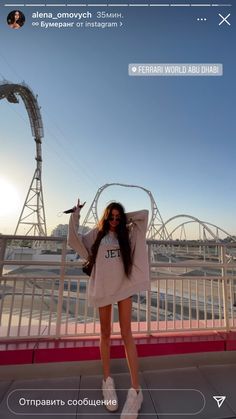 a woman standing on top of a bridge next to a roller coaster