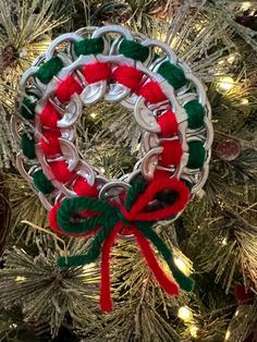 a christmas ornament hanging on a tree with red, green and white ribbon