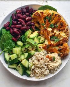 a white plate topped with rice, beans and veggies next to other foods