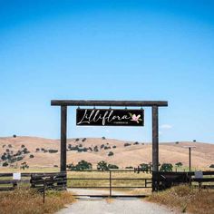 a sign that is on the side of a road in front of a field and hills