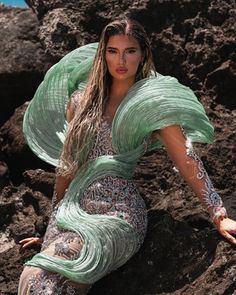 a woman in a green dress sitting on rocks