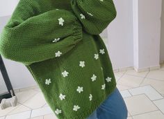 a woman wearing a green sweater with shamrocks on it is taking a selfie