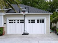 a basketball hoop in front of a house with two garage doors on the outside and one side