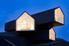 two houses are lit up at night on top of each other, with windows open to let in light