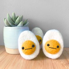 two stuffed eggs sitting next to a succulent plant