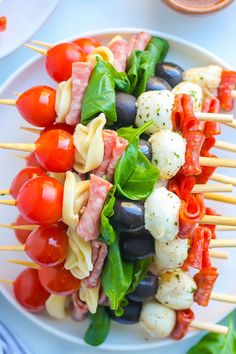 a white plate topped with skewered vegetables and veggies on toothpicks