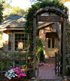 the entrance to a garden with flowers and plants in pots on either side of it