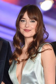 a woman with long hair wearing a silver dress and posing for the camera at an event