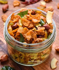 a glass jar filled with fruit and nuts on top of a wooden table next to leaves