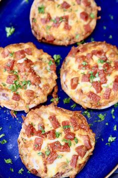 four small pizzas on a blue plate with parsley sprinkled around them