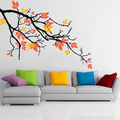 a living room filled with furniture and a tree branch wall decal on the wall