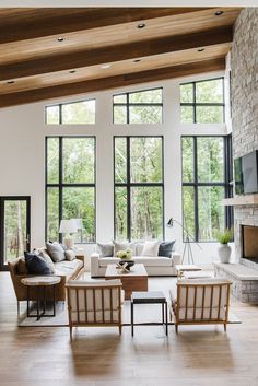 a living room filled with lots of furniture next to a fire place and large windows