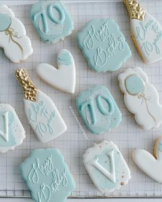 decorated cookies with blue icing and white frosting are arranged on a tablecloth