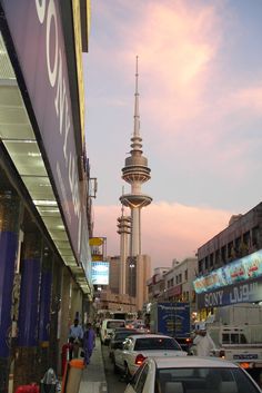 cars are parked on the street in front of tall buildings with spires behind them